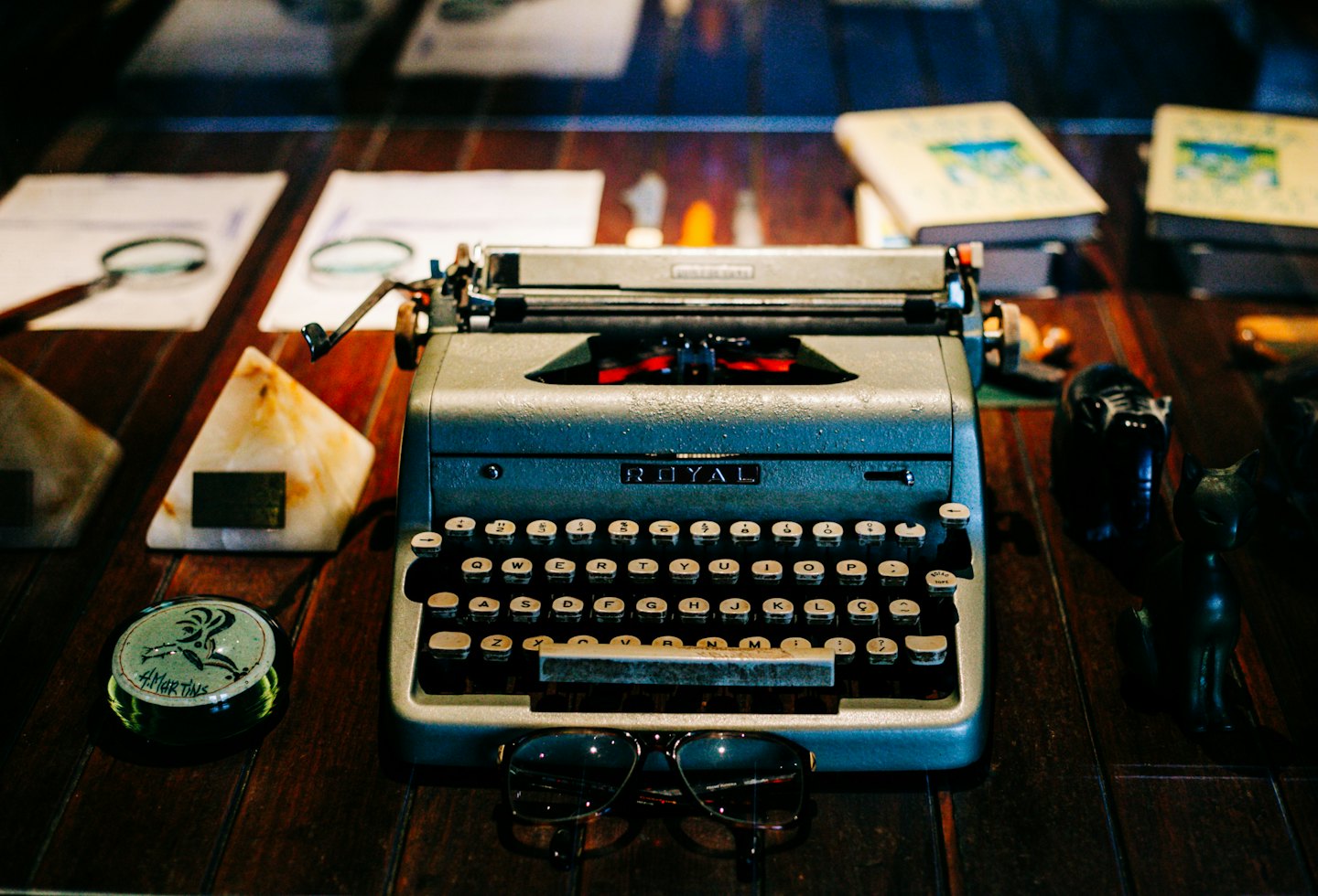 Una macchina da scrivere vintage su una scrivania con occhiali nelle vicinanze.